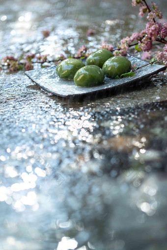 雨中水面上的青团和桃花圆形写实图片