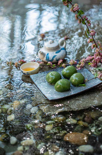 水面上的青团和茶具植物氛围摄影图