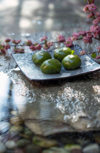 水面上的青团和桃花枝健康食物写实摄影图