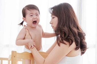 年轻妈妈抱着哭着的宝宝中国高端摄影图