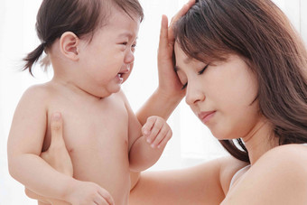 年轻妈妈抱着哭着的宝宝中国人清晰摄影图