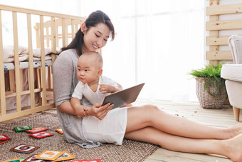 年轻妈妈在家边看孩子边使用电脑互联网清晰素材