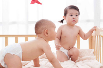 两个可爱宝宝坐在床上玩耍男孩高质量摄影图