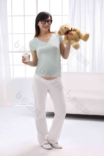 孕妇手拿玩具熊及奶瓶