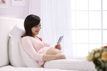 孕妇坐在床上看超声波照片