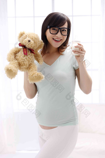 孕妇手拿玩具熊及奶瓶站着氛围图片