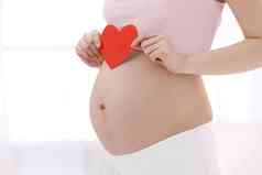 孕妇拿着心形剪纸放在肚子上