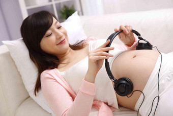 孕妇把耳机放在肚子上拿着清晰摄影