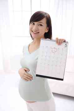 孕妇拿着日历牌