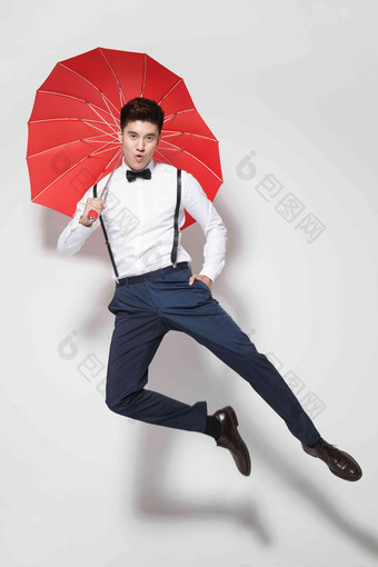 青年男人拿着心形红雨伞跳跃