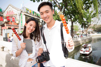 青年情侣旅游拿着糖葫芦浪漫写实图片