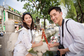 青年情侣旅游拿着糖葫芦旅行高质量摄影图