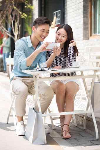 青年情侣坐在咖啡馆看手机