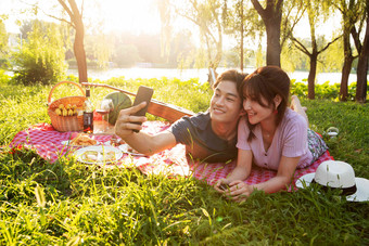 趴在草地上拍照的幸福情侣