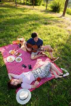 坐在公园里弹吉他的幸福情侣