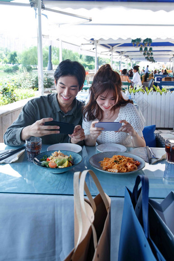青年情侣在餐厅里用手机拍照健康食物写实相片
