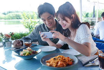 青年情侣在餐厅里用手机拍照东方人高质量场景