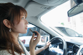 青年女人在汽车里化妆