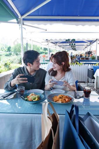 青年情侣在餐厅里用手机拍照浪漫拍摄