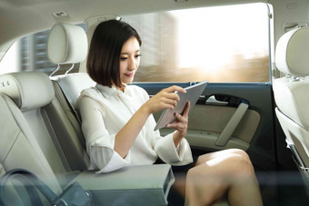 青年女人坐在汽车里看平板电脑旅行照片