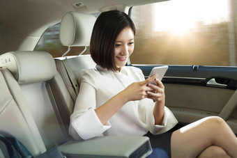 青年女人坐在汽车里看手机时尚清晰照片