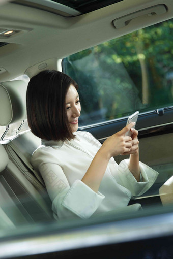 青年女人坐在汽车里看手机便利高质量影相