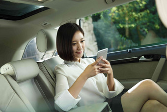青年女人坐在汽车里看手机车座素材