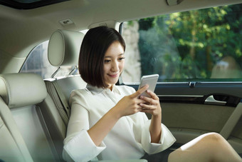 青年女人坐在汽车里看手机东亚氛围照片