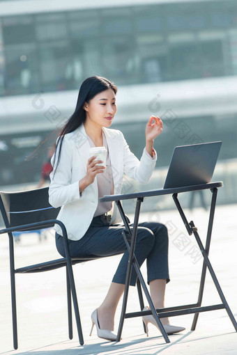 商务女士坐在户外使用笔记本电脑