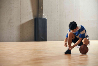 青年男人在<strong>篮球</strong>场上系鞋带