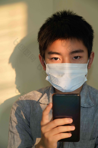 戴口罩的男孩看手机预防病毒男孩高端图片