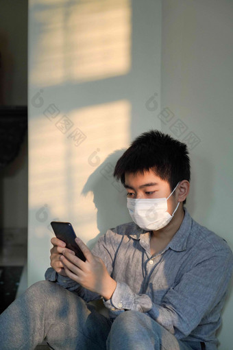 戴口罩的男孩看手机生病摄影图