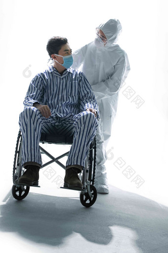 医务工作者推着坐轮椅的患者治疗写实摄影图