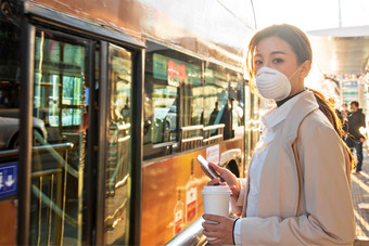 戴口罩的年轻女人站在公交车站<strong>白昼</strong>高质量拍摄