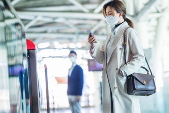 戴口罩的年轻女人站在地铁站台上