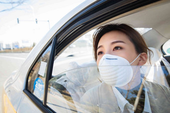 年轻女人戴口罩乘坐汽车车窗写实拍摄