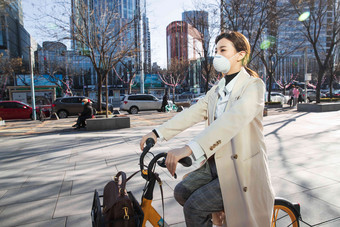 戴口罩的年轻女人骑共享单车防污染口罩清晰场景
