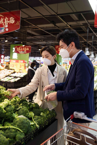 青年夫妇戴口罩在超市挑选蔬菜