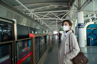 戴口罩的年轻女人站在<strong>地铁</strong>站台上