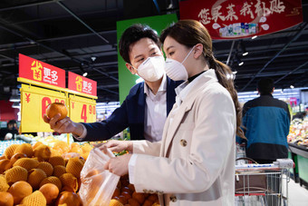 青年夫妇戴口罩在超市挑选水果