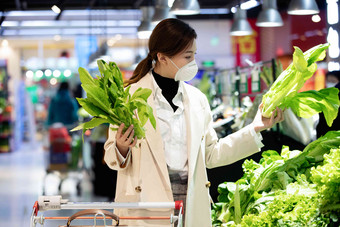 戴口罩的青年女人在超市购买<strong>青菜</strong>