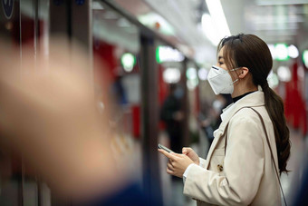 戴口罩的年轻女人站在地铁站台上