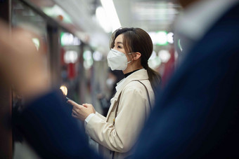 戴口罩的年轻女人站在地铁站台上