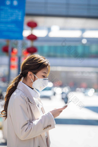 戴口罩的青年女人看手机