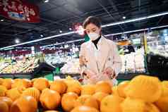 戴口罩的青年女人在超市购买水果