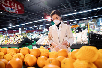 戴口罩的青年女人在超市购买水果