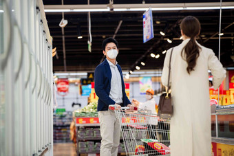 青年夫妇戴口罩在超市购物