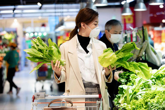 戴口罩的青年女人在<strong>超市</strong>购买青菜蔬菜写实<strong>照片</strong>