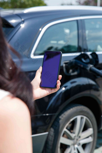 青年女人使用手机自助充电汽车