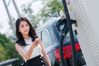 青年女人使用手机自助充电汽车节能高清照片